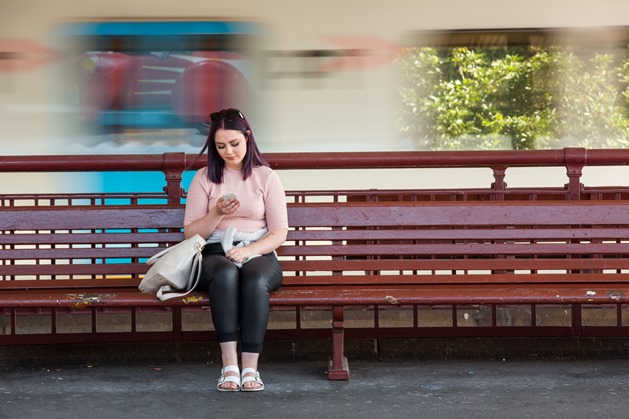 Young person sat on wooden bench, using mobile phone