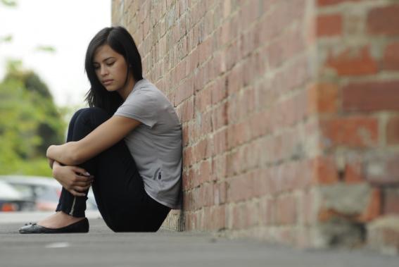 Person sat against brick wall